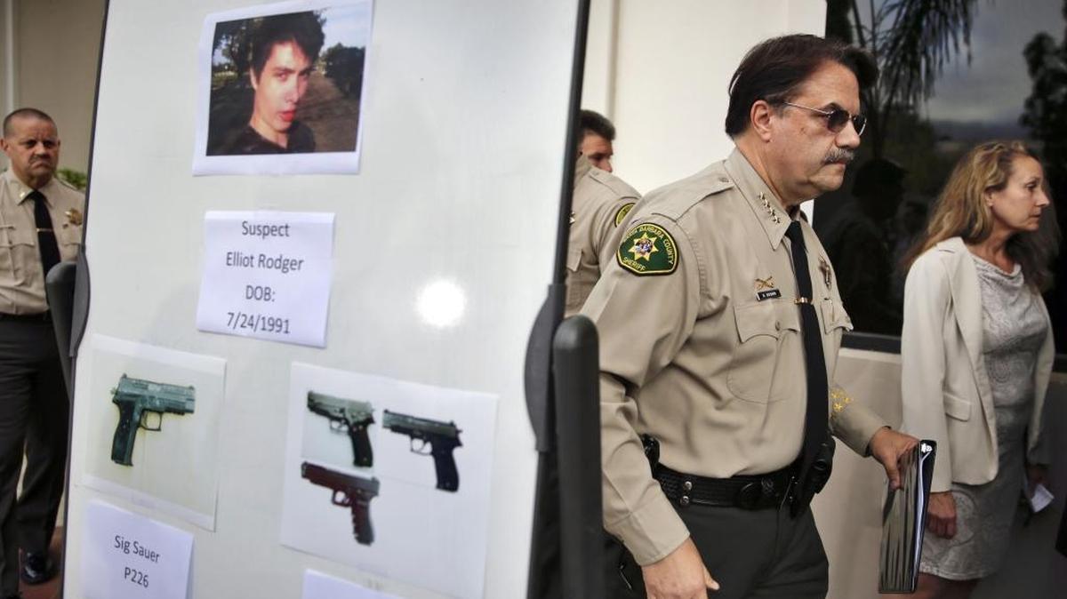FILE - In this May 24, 2014 file photo, Santa Barbara County Sheriff Bill Brown, right, walks past a board displaying photos of gunman Elliot Rodger and the weapons he used in a mass shooting in Isla Vista, Calif., after a news conference in Santa Barbara, Calif. A growing number of states have passed laws or are considering bills allowing courts to temporarily remove guns from individuals deemed a danger to themselves or others, an intervention that advocates say stops shootings and suicides by disturbed individuals. (AP Photo/Jae C. Hong, File)