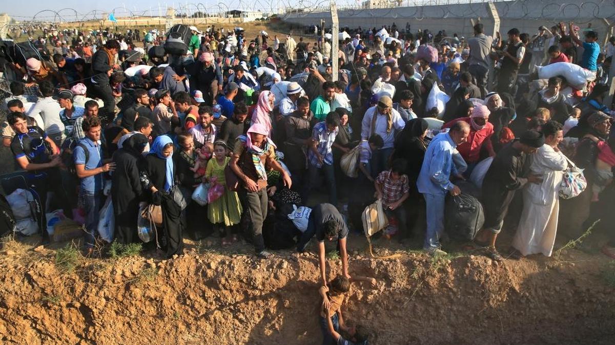 Syrian refugees walk into Turkey after breaking the border fence and crossing from Syria in Akcakale, Sanliurfa province, southeastern Turkey, Sunday, June 14, 2015. . (AP)
