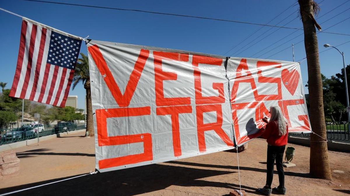 Las Vegas resident Nancy Cooley signs a Vegas Strong banner honoring the victims of a mass shooting on Thursday, Oct. 5, 2017, in Las Vegas. In the days following the shooting, when most Americans were expressing sympathy and unity, a small group seized on side issues to gin up division and outrage.
