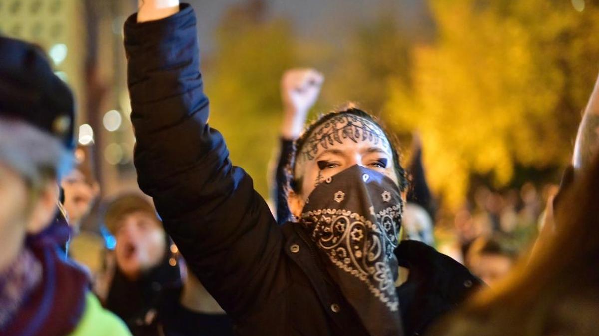 People gather at Portland City Hall to protest the election of president-elect, Donald Trump, Friday, Nov. 11, 2016, in Portland, Ore. Hundreds of protesters traveled through downtown Portland streets Friday night while others converged at an intersection, not budging as police told them the activity amounted to unlawful assembly. (Mark Graves via AP)