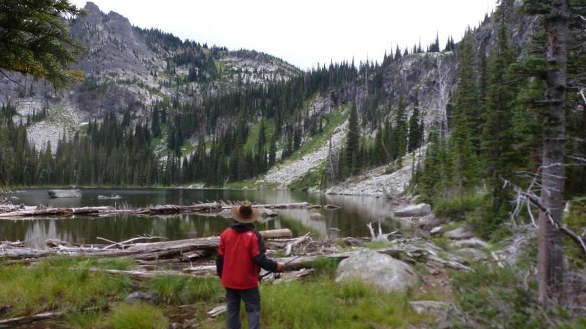A hiking angler approaches an alpine lake in the Gospel Hump Wilderness.