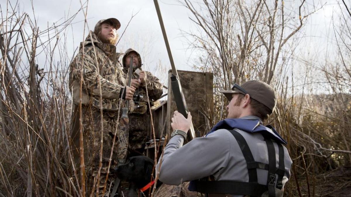Steve Ross, right, an Idaho Department of Fish and Game senior conservation officer, checks the shotguns of waterfowl hunters Jon Adams, left, and Jason Titone during a patrol of the Snake River near Hagerman.