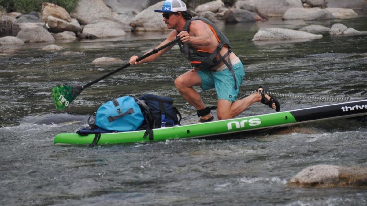 Jed Conklin kneels forward to rock his high-centered SUP off a boulder in the Spokane River during a four-day trip to paddle the entire 112 miles of the river.
