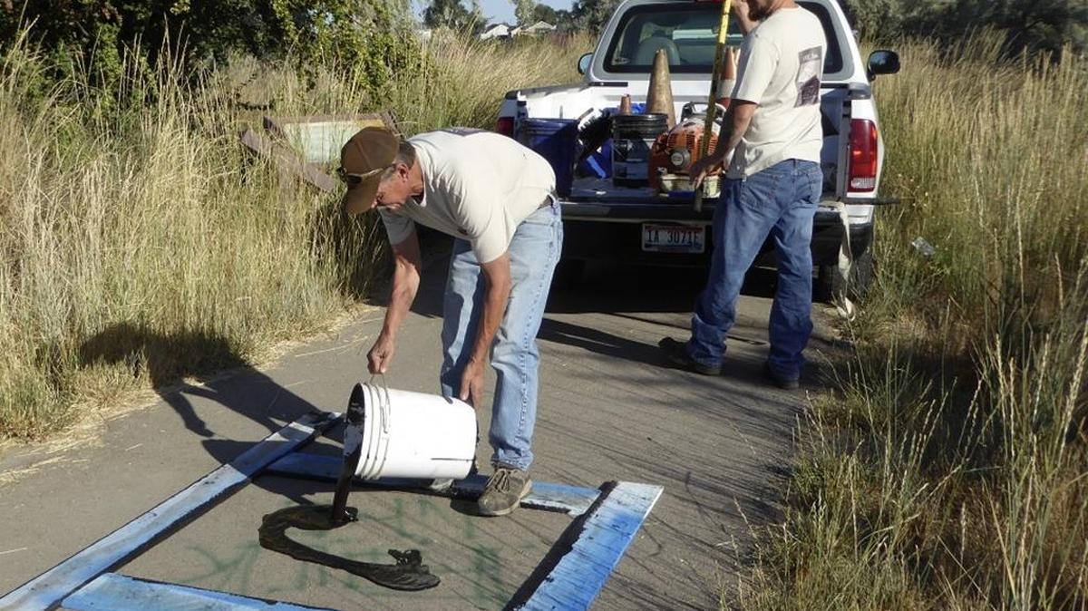 Father-son duo Ron and Ross Carrico, owners of AMU Inc. in Nampa, applied asphalt sealer to cover the graffiti along a paved walking path at Wilson Ponds.