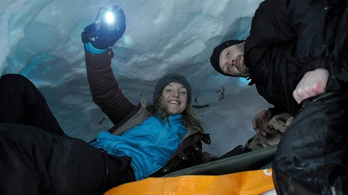 Lexi Nelson and Shannon Lavada check out the newly carved snow cave they built near Lookout Pass during an overnight snowshoeing trek with the Spokane Mountaineers.