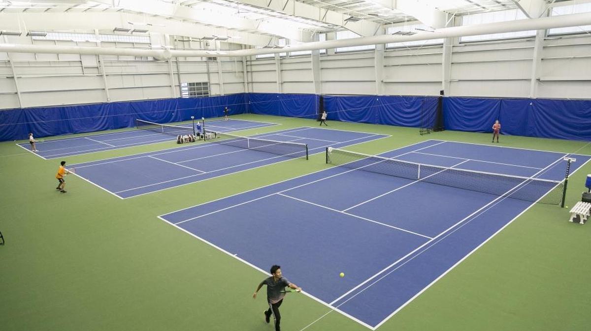 Adam Tzeng (bottom) returns a shot during a practice session at the Eagle Tennis Club, which has 12 indoor courts.