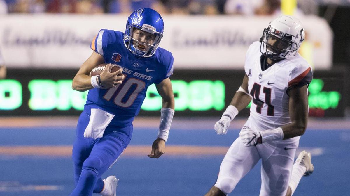 Boise State quarterback Chase Cord picks up a first down on a keeper pursued by Connecticut linebacker Marshe Terry.