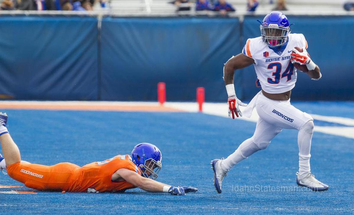 Boise State running back Robert Mahone sprints by linebacker Benton Wickersham after evading two tackles during the annual spring game scrimmage Saturday, April 14, 2018, at Albertsons Stadium in Boise.