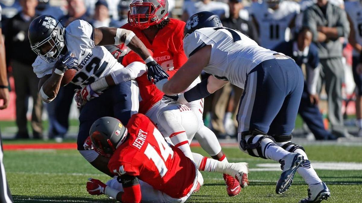 Utah State running back Devante Mays is taken down by New Mexico defender during Saturday’s game in Albuquerque, N.M.