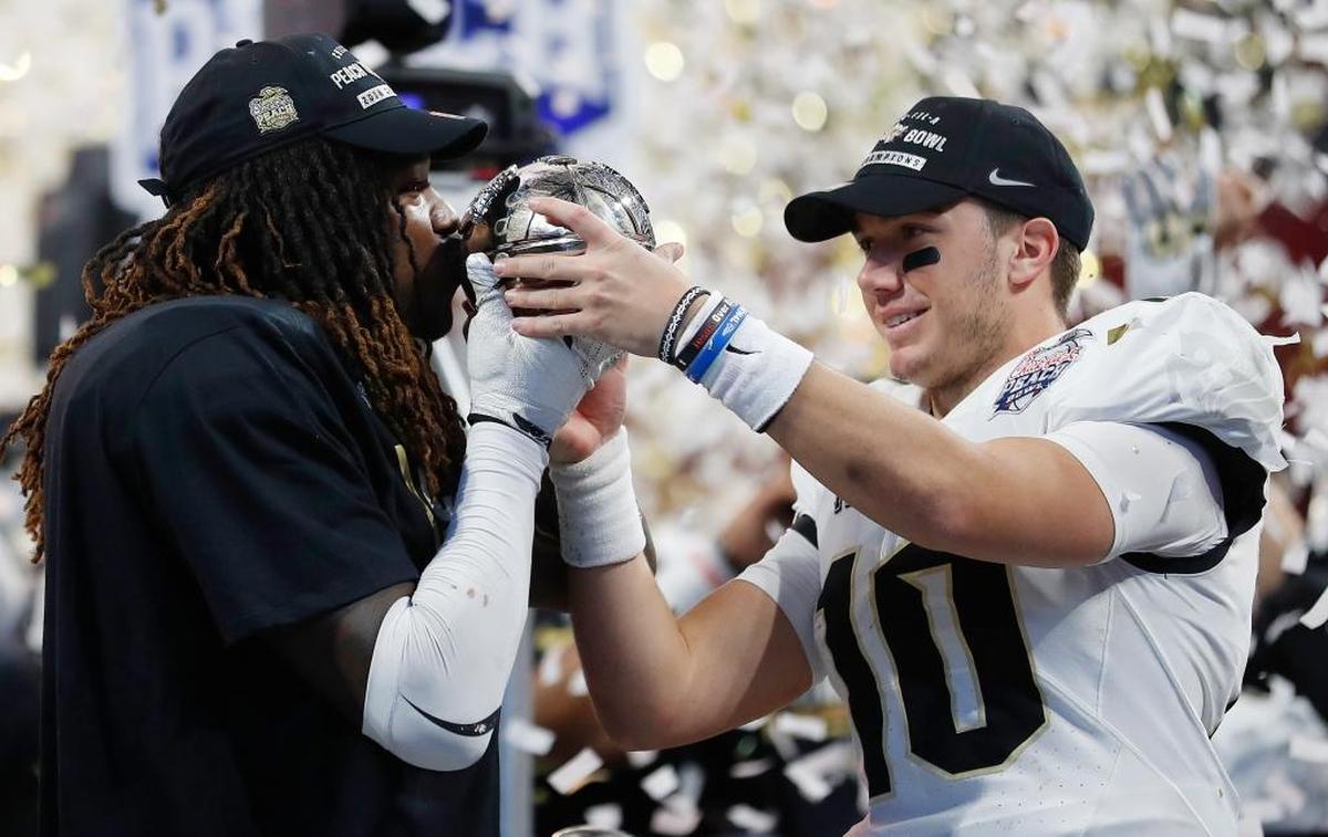 UCF linebacker Shaquem Griffin, left, kisses the championship trophy as quarterback McKenzie Milton looks on after the Peach Bowl on Jan. 1, 2018, in Atlanta. UCF beat Auburn 34-27.