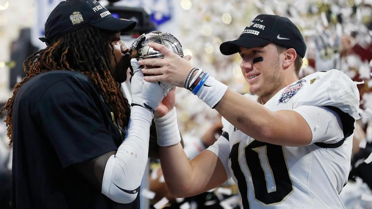 Central Florida linebacker Shaquem Griffin, left, kisses the championship trophy as Central Florida quarterback McKenzie Milton looks on after the Peach Bowl on Jan. 1 in Atlanta. Central Florida beat Auburn 34-27.