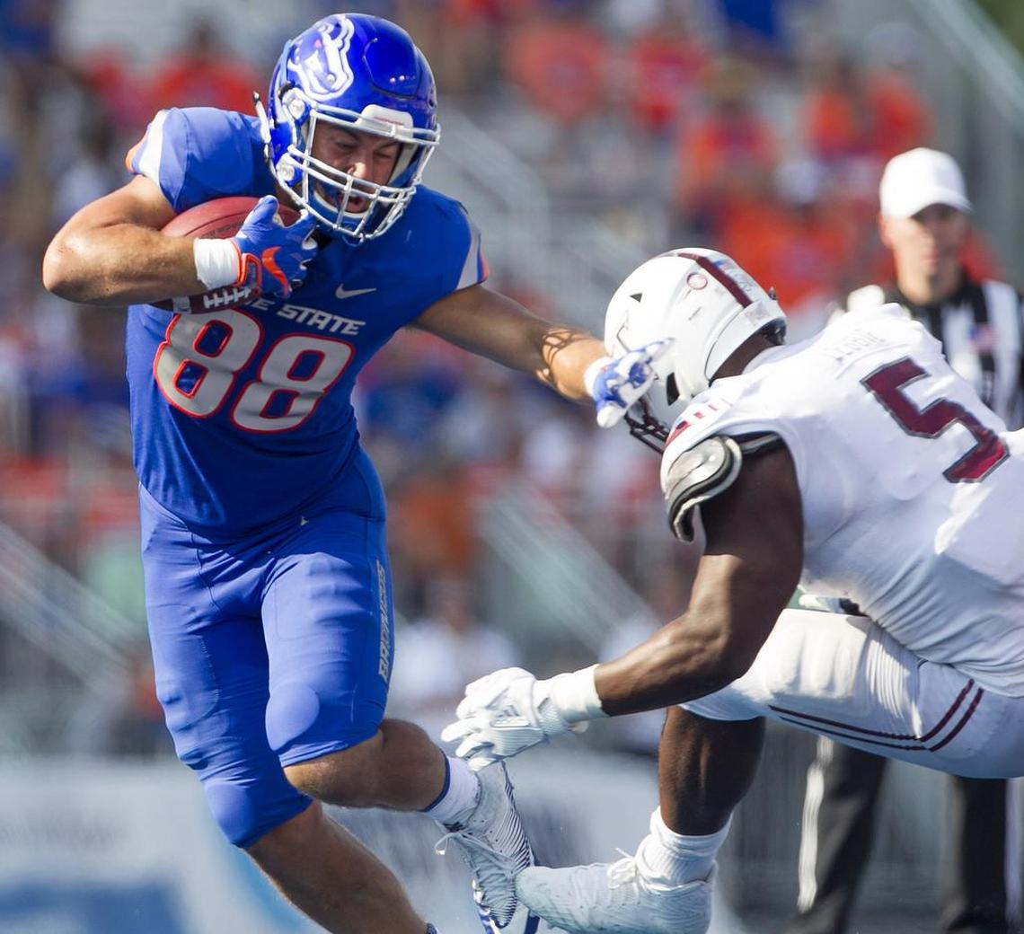 Boise State tight end Jake Roh fights off a tackle by Troy linebacker Sam Lebbie.