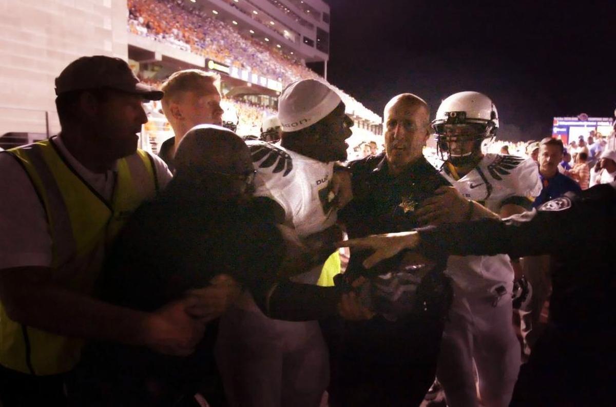LeGarrette Blount, center, is pushed off the field by coaches, police and security personnel at the end of Oregon’s 2009 game at Boise State.