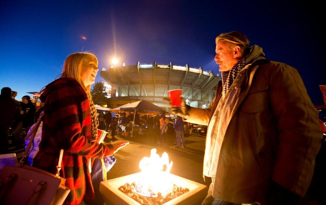 Patrick Drake, right, and Katie Kelso keep warm by a fire while tailgating outside of Albertsons Stadium before the Boise State football game against Air Force in 2015. Fans may no longer have to retreat to their tailgates to enjoy a beer under new rules approved by the Idaho State Board of Education.