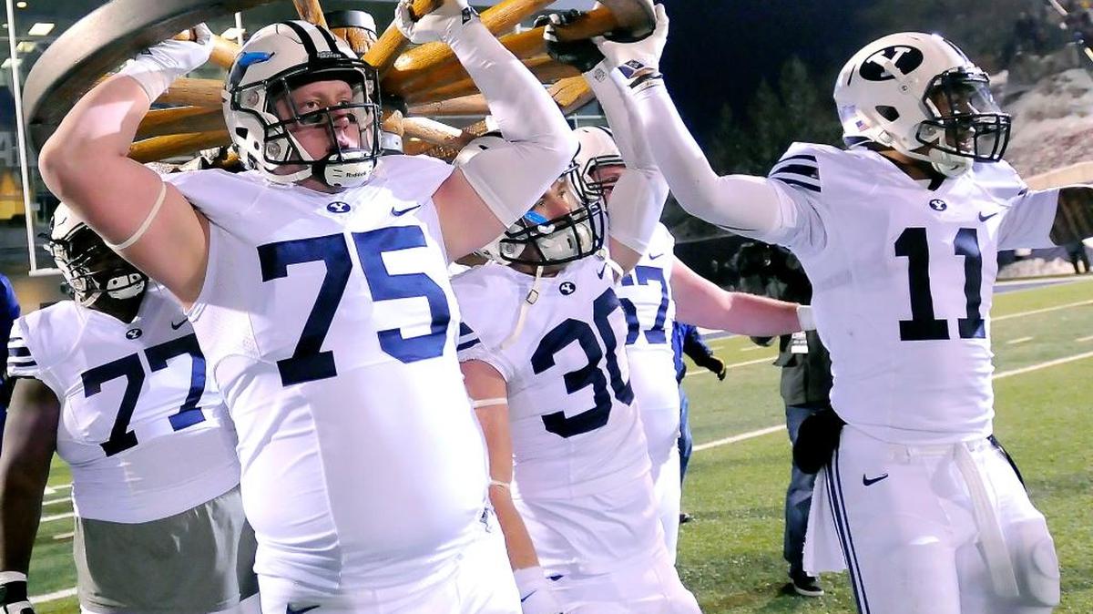 BYU players carry the Wagon Wheel Trophy after BYU defeated Utah State 51-28 during an NCAA college football game Saturday, Nov. 28, 2015, in Logan, Utah.