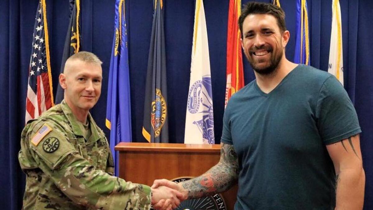 Maj. David Darney of the Idaho Army National Guard shakes hands with former NFL and Boise State football star Daryn Colledge after his enlistment ceremony in Boise on Tuesday.