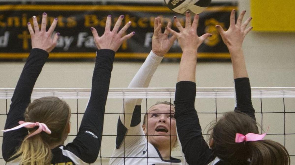 Skyview’s Dani Nay (12) goes for a hit between Bishop Kelly’s Reilly Cronin (5) and Molly Adcox (11) in the 4A District Three championship volleyball match Oct. 22, 2014.