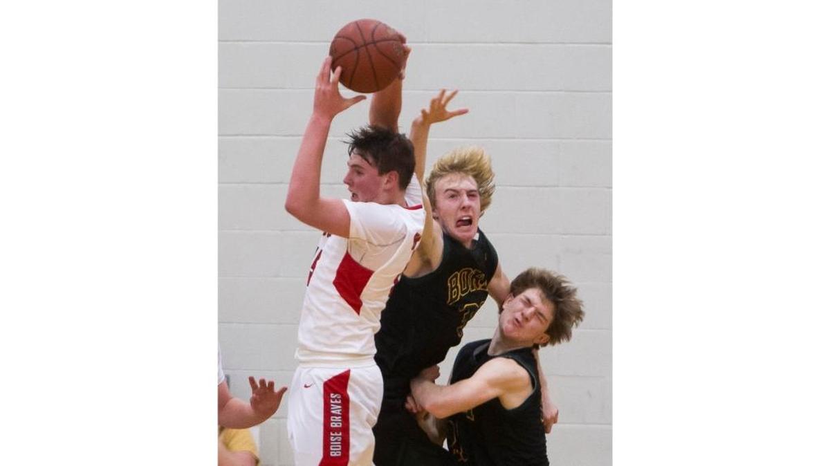 Boise High junior Cole Alton brings down a defensive rebound in a struggle with Borah’s Austin Bolt and Jay Ahlstrom on Jan. 20 at Boise High.