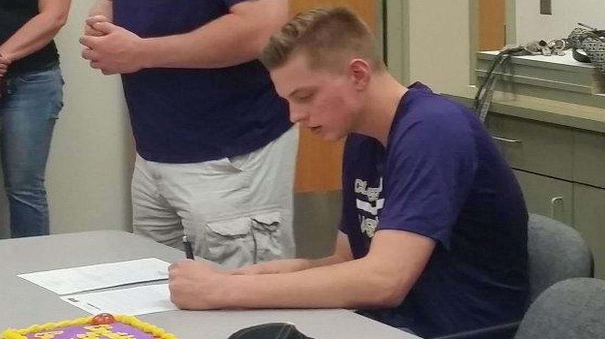 Boise’s Evan Henning signs a letter of intent to the College of Idaho as Yotes’ head coach Scott Garson, second from left, looks on.