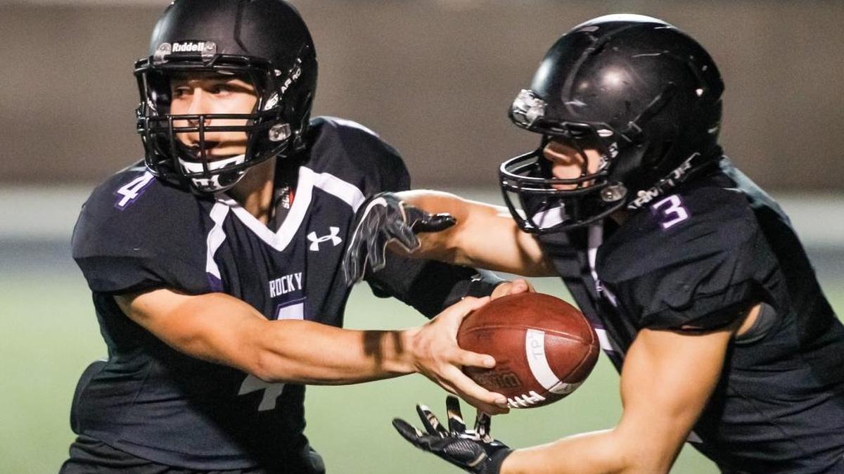 Rocky Mountain quarterback Tre Page, left, hands off to running back Carter Kuehl during Friday’s 5A state playoff game against Kuna at Rocky Mountain High in Meridian.