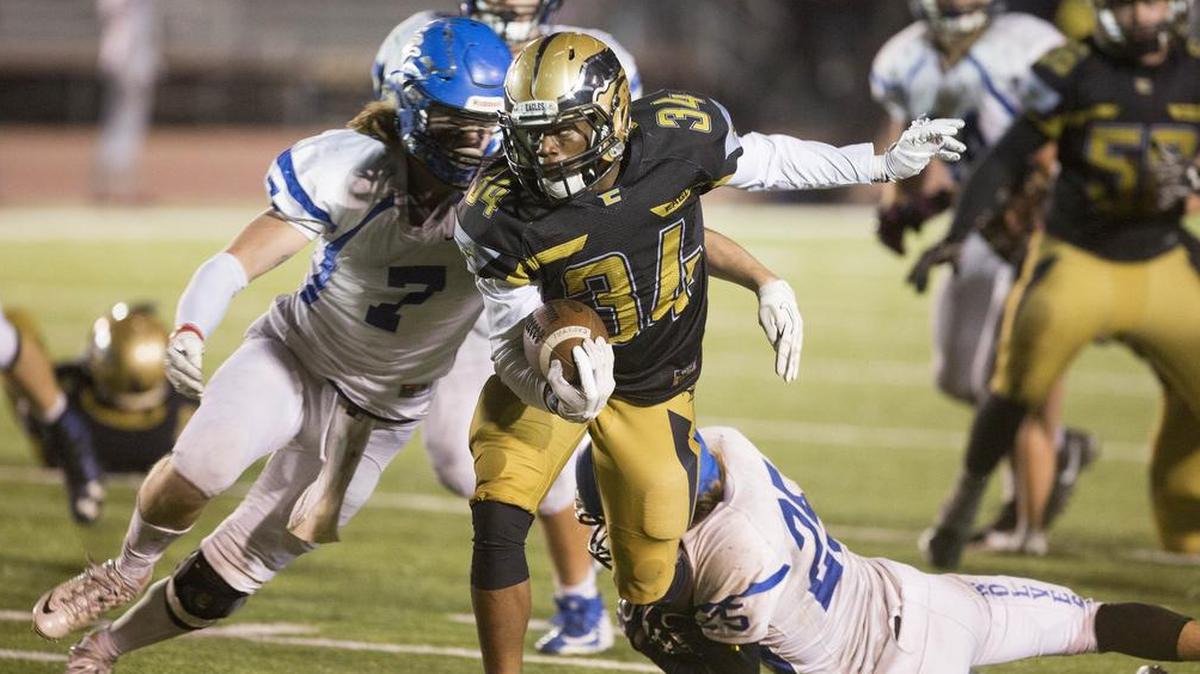 Capital High’s Sam Sessou-Djokoto runs through tackle attempts by Timberline’s Stone Mason and Dylan Herberg (7) during their 5A playoff game Friday night at Dona Larsen Park.