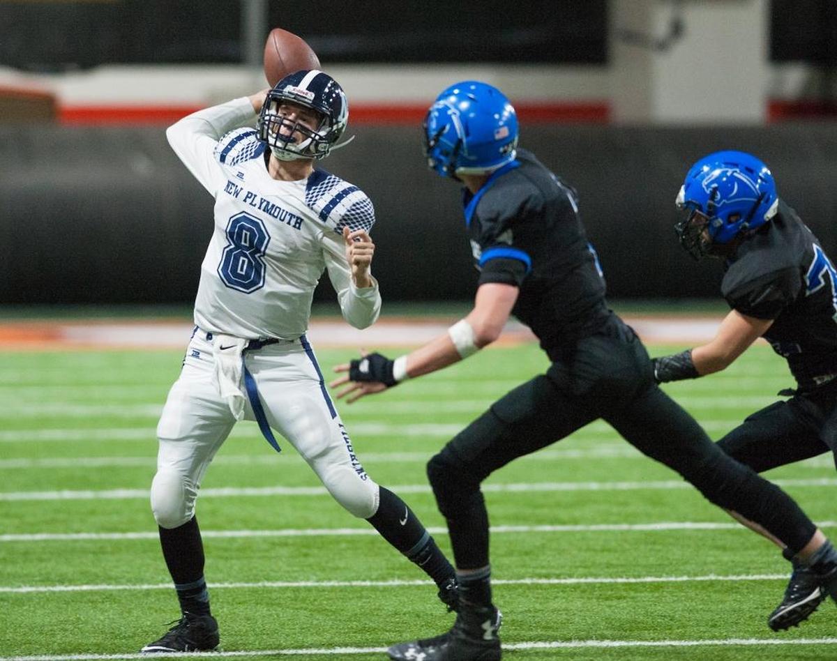 New Plymouth quarterback Austin Robinson gets rid of the ball as Firth’s Grayson Nelson and Clayton Gain pursue him in their playoff game Friday night at Holt Arena in Pocatello.