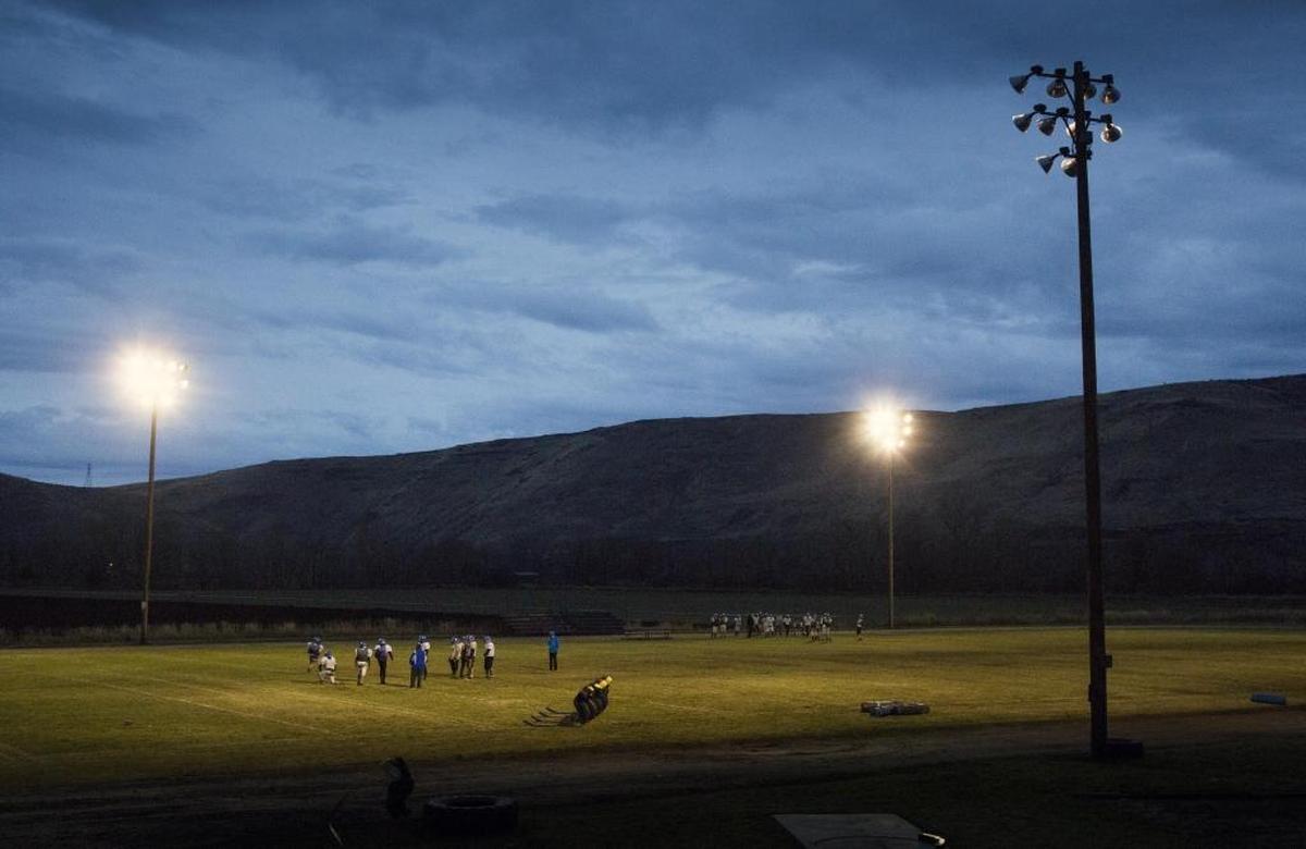 The Tri-Valley Titans, a combination of students from Cambridge and Midvale schools, practice under the lights Wednesday at their field at Cambridge High.