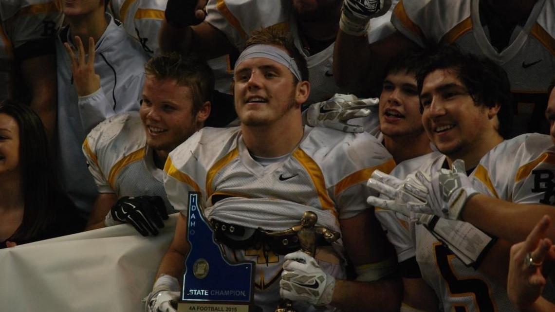 Bishop Kelly senior Jon Baumgardner holds the 4A state championship trophy Saturday as teammates hold up three fingers around him, representing the third straight title the Knights have won.