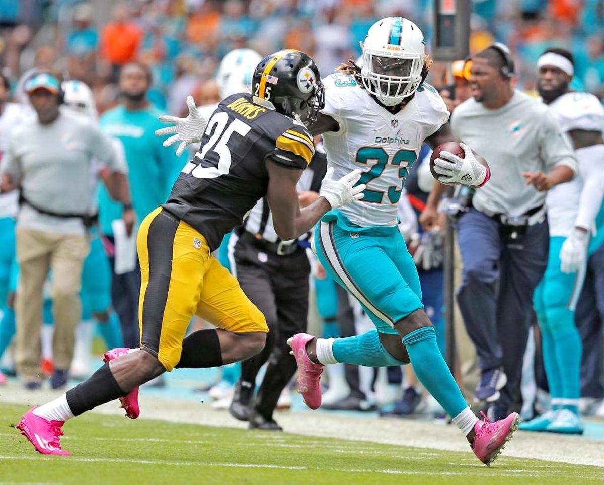 Miami Dolphins running back Jay Ajayi runs for a first down as Pittsburgh Steelers cornerback Artie Burns chases during the second quarter Sunday at Hard Rock Stadium in Miami Gardens, Fla.